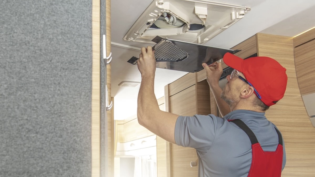 Un homme qui répare la ventilation d'une roulotte.